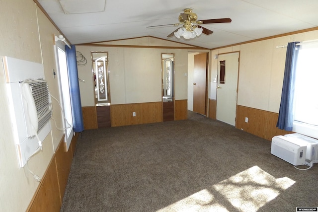 carpeted spare room featuring an AC wall unit, wooden walls, ceiling fan, and vaulted ceiling