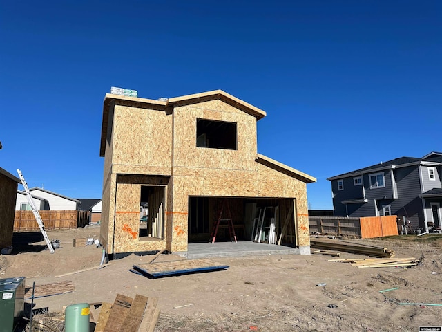 rear view of property with a garage, fence, and stucco siding