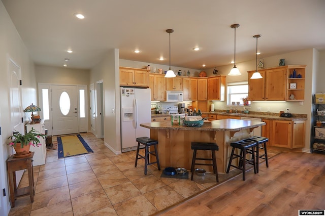 kitchen with a breakfast bar, white appliances, sink, pendant lighting, and a center island