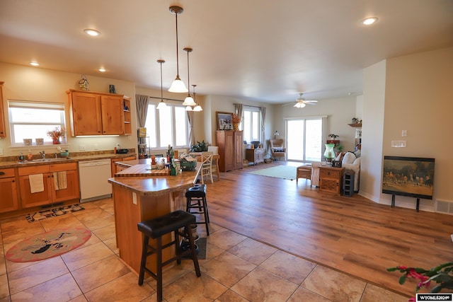 kitchen featuring white dishwasher, light wood-type flooring, a breakfast bar area, and a wealth of natural light