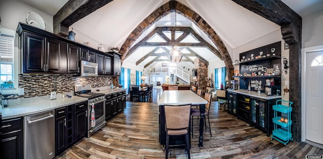 kitchen with stainless steel appliances, vaulted ceiling with beams, dark hardwood / wood-style floors, plenty of natural light, and a kitchen island