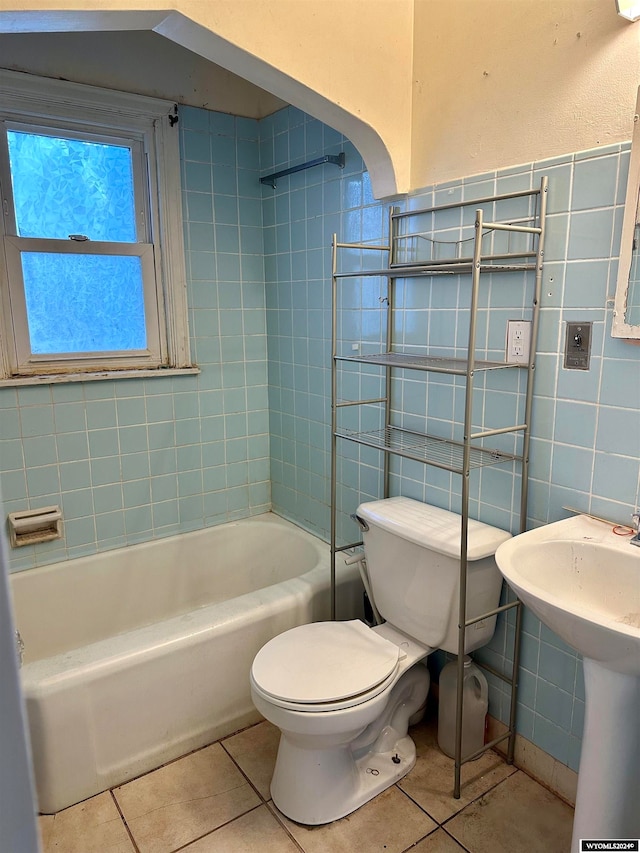 full bathroom featuring tile patterned floors, tiled shower / bath combo, sink, tile walls, and toilet