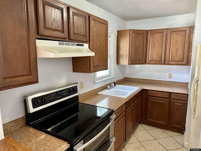 1323 Cherry St, Rawlins, WY 82301 - kitchen featuring stainless steel range with electric cooktop, under cabinet range hood, freestanding refrigerator, and light tile patterned floors