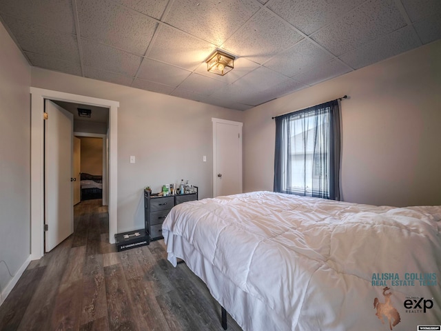 bedroom with a paneled ceiling and dark hardwood / wood-style floors