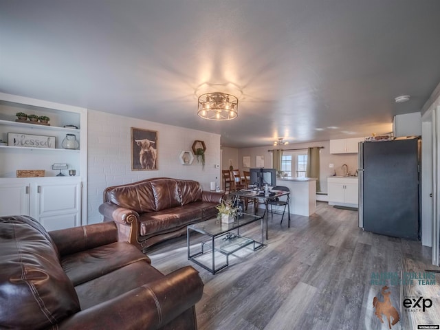 living room featuring hardwood / wood-style floors, baseboard heating, and sink