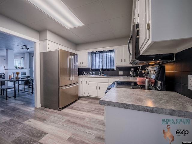 kitchen with light wood-type flooring, white cabinetry, stainless steel appliances, and a wealth of natural light