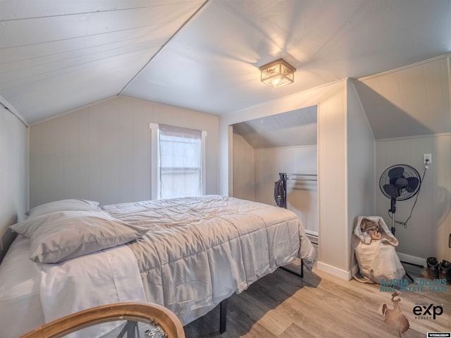 bedroom with wood-type flooring, vaulted ceiling, and wood walls