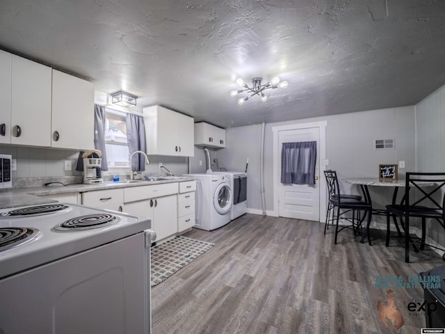 kitchen featuring white cabinets, electric stove, sink, light hardwood / wood-style flooring, and washer / dryer