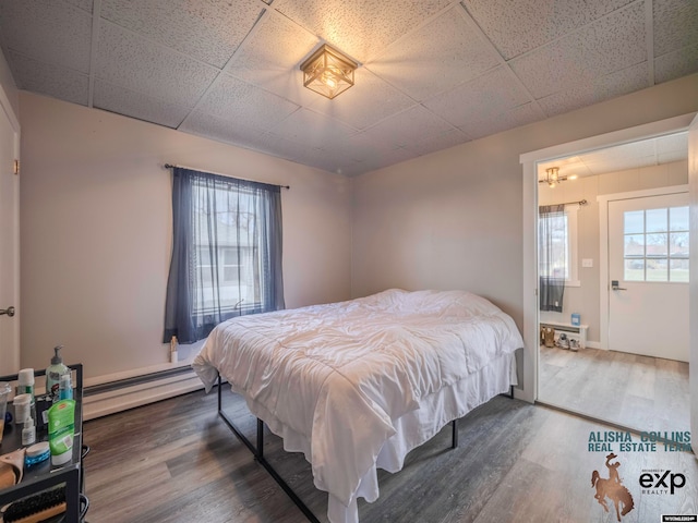 bedroom featuring dark hardwood / wood-style floors, a drop ceiling, and a baseboard radiator