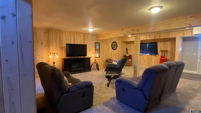 living room featuring carpet flooring, wood walls, and a fireplace