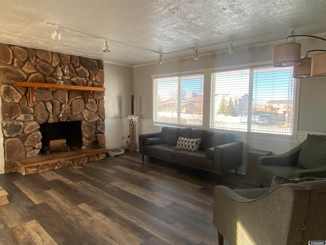 living room with rail lighting, dark hardwood / wood-style floors, ornamental molding, a fireplace, and a textured ceiling