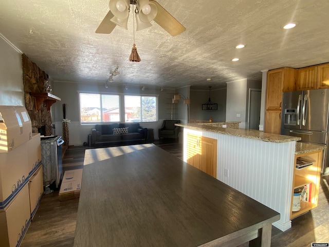 kitchen featuring hanging light fixtures, dark hardwood / wood-style floors, ceiling fan, a textured ceiling, and light stone counters