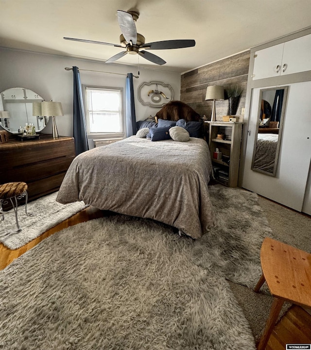 bedroom with ceiling fan and wooden walls