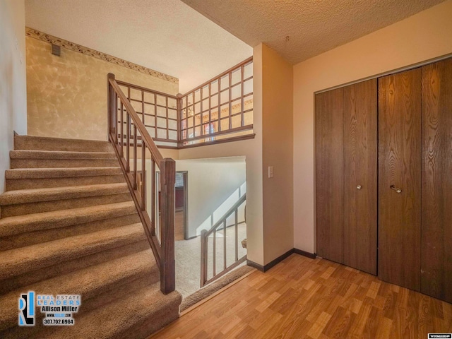 staircase with hardwood / wood-style floors and a textured ceiling