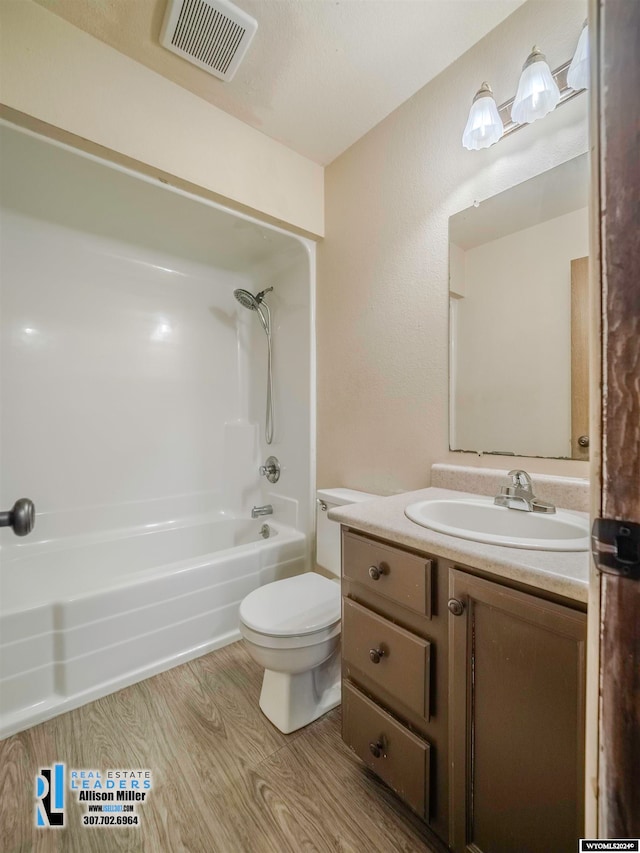 full bathroom featuring hardwood / wood-style floors, vanity, bathing tub / shower combination, and toilet