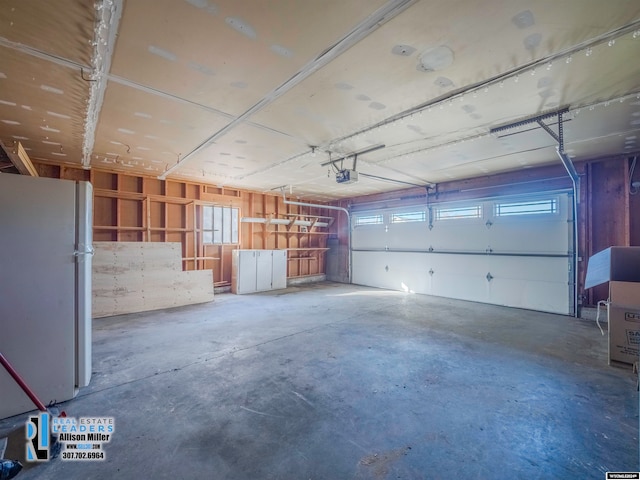 garage with a garage door opener and white refrigerator