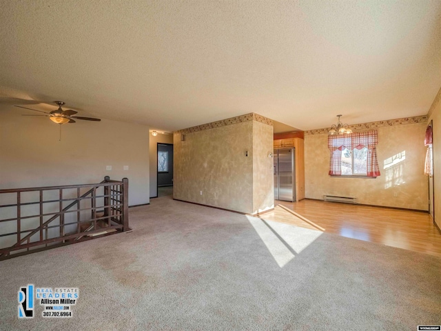 spare room with baseboard heating, ceiling fan with notable chandelier, wood-type flooring, and a textured ceiling