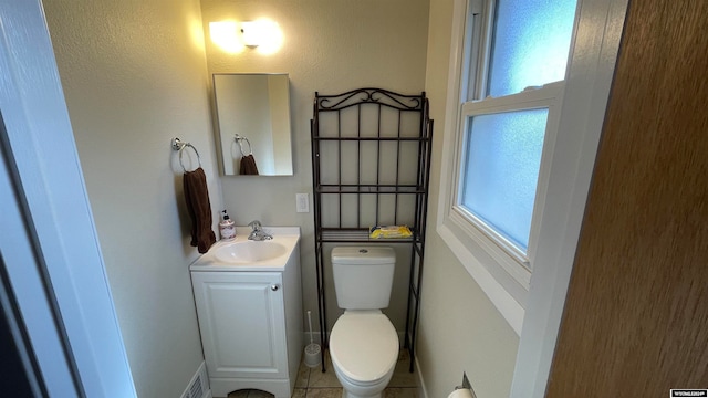 bathroom with toilet, vanity, and tile patterned floors