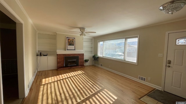 unfurnished living room featuring ornamental molding, built in shelves, ceiling fan, light hardwood / wood-style flooring, and a fireplace