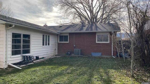 back of house with central AC and a lawn