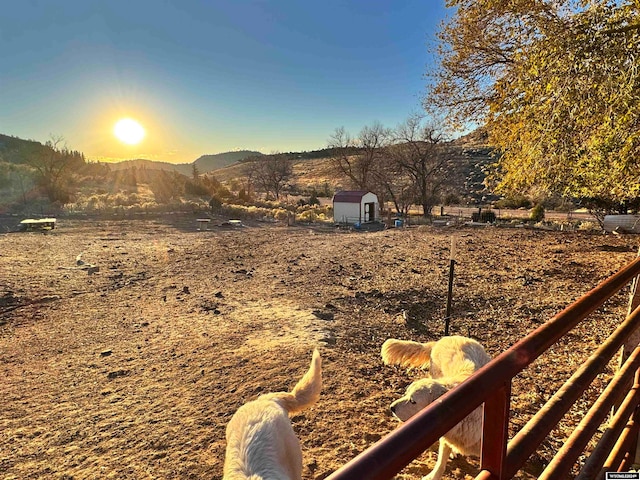 view of yard with a mountain view, a rural view, and a storage shed