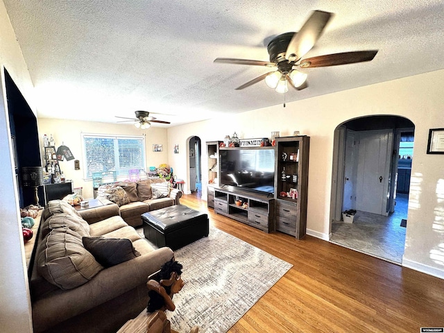 living room with hardwood / wood-style flooring, ceiling fan, and a textured ceiling