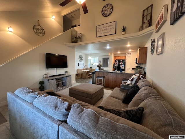 carpeted living room featuring ceiling fan and high vaulted ceiling