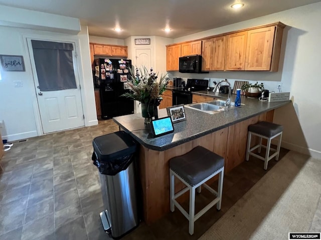 kitchen with black appliances, kitchen peninsula, sink, and a breakfast bar area