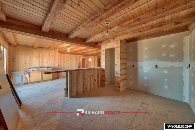 kitchen with beam ceiling, wood walls, light brown cabinetry, and wood ceiling