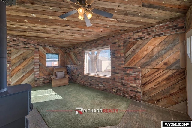 323 Bridge Ave, Worland, WY 82401 - unfurnished room featuring brick wall, a wood stove, wooden ceiling, carpet, and ceiling fan