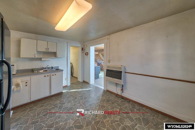 kitchen featuring heating unit, white cabinetry, and sink