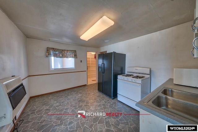 kitchen featuring heating unit, white gas stove, black fridge with ice dispenser, and sink