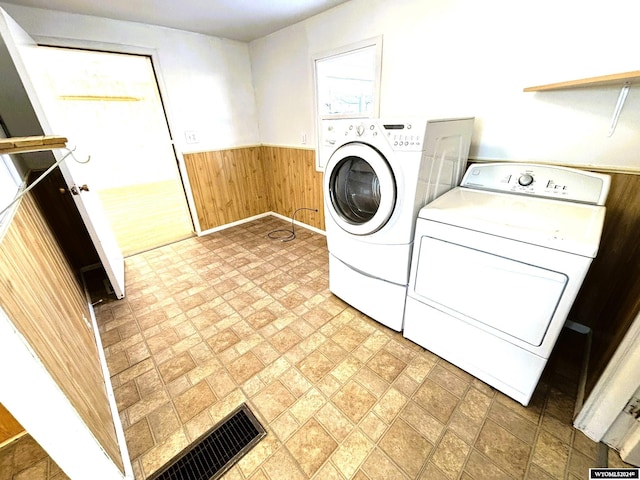 washroom with washing machine and dryer and wooden walls