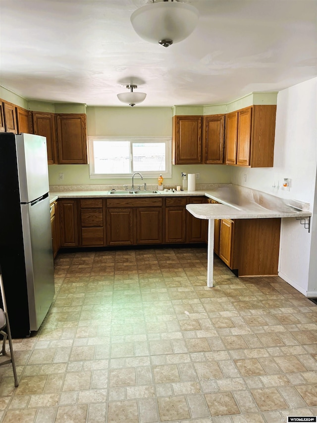 kitchen featuring kitchen peninsula, stainless steel refrigerator, and sink