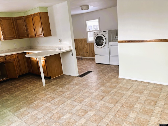 washroom with washer and dryer, cabinets, and wood walls