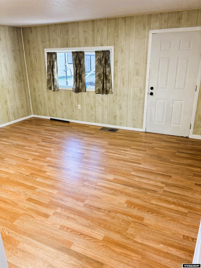 spare room with wood walls and light wood-type flooring