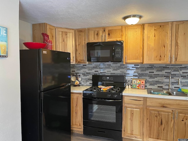 kitchen featuring backsplash, sink, hardwood / wood-style floors, and black appliances