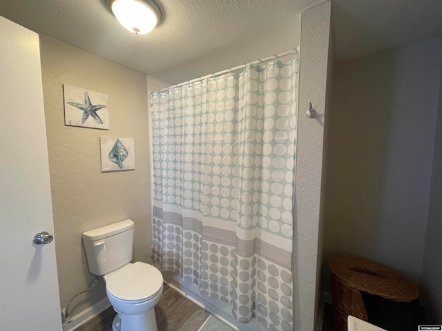 bathroom with a shower with curtain, toilet, wood-type flooring, and a textured ceiling