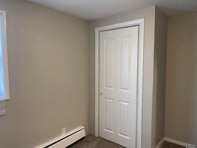 unfurnished bedroom featuring a closet, a baseboard radiator, and dark carpet