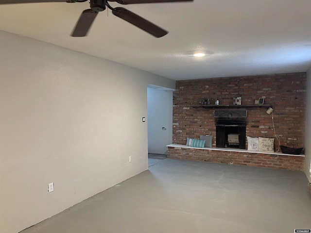 unfurnished living room featuring ceiling fan, concrete flooring, and a brick fireplace