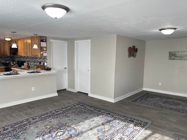 interior space with a textured ceiling, backsplash, and dark wood-type flooring