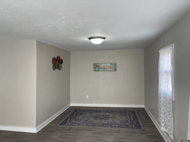 spare room featuring dark hardwood / wood-style flooring and a textured ceiling