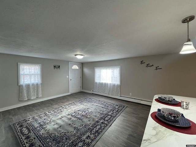 foyer entrance featuring a textured ceiling, baseboard heating, and dark wood-type flooring