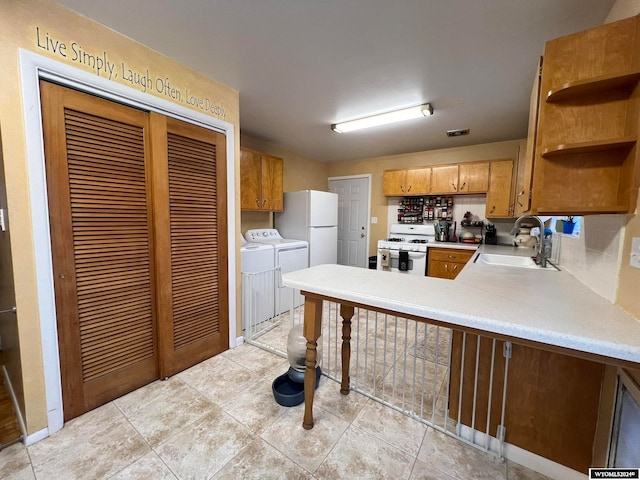 kitchen featuring sink, light tile patterned floors, washer and dryer, and white appliances