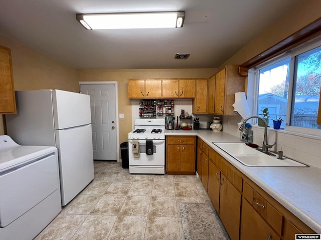 kitchen featuring washer / dryer, white appliances, tasteful backsplash, and sink