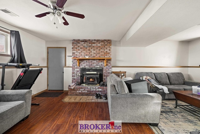 living room with dark hardwood / wood-style floors, ceiling fan, and a wood stove