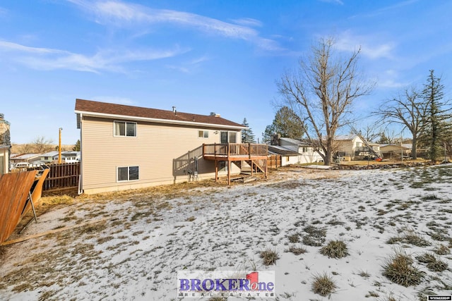 snow covered rear of property with a wooden deck