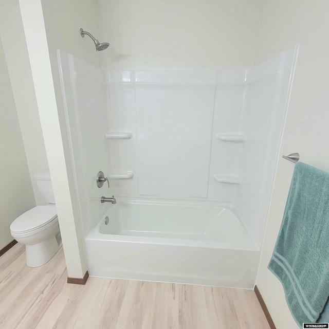 bathroom with hardwood / wood-style floors,  shower combination, and toilet