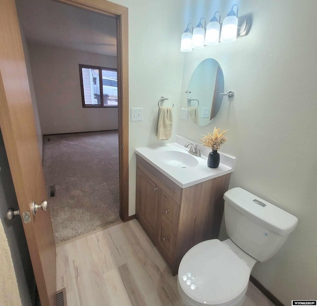 bathroom with hardwood / wood-style floors, vanity, and toilet