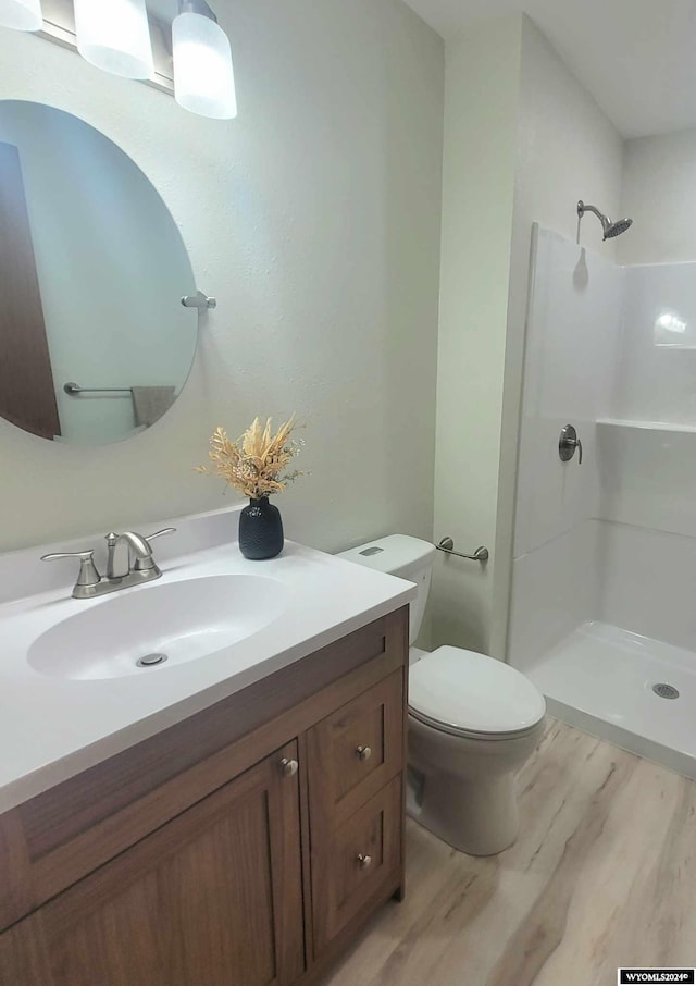 bathroom featuring hardwood / wood-style floors, vanity, toilet, and walk in shower